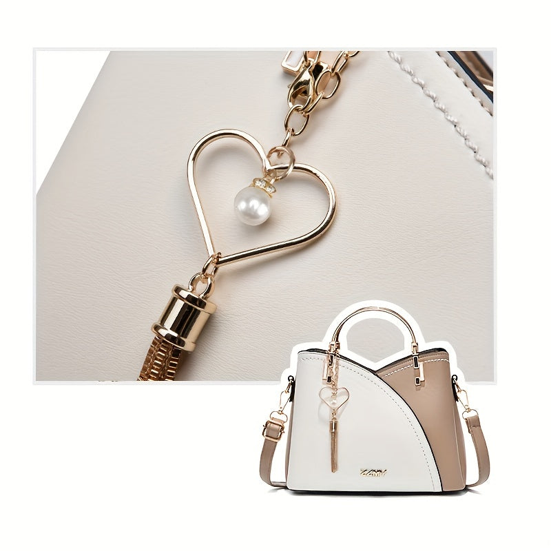 Borsa a mano elegante in pelle bianca e beige con ciondolo a cuore e perla, dettagli dorati, design moderno. Accessorio moda donna.