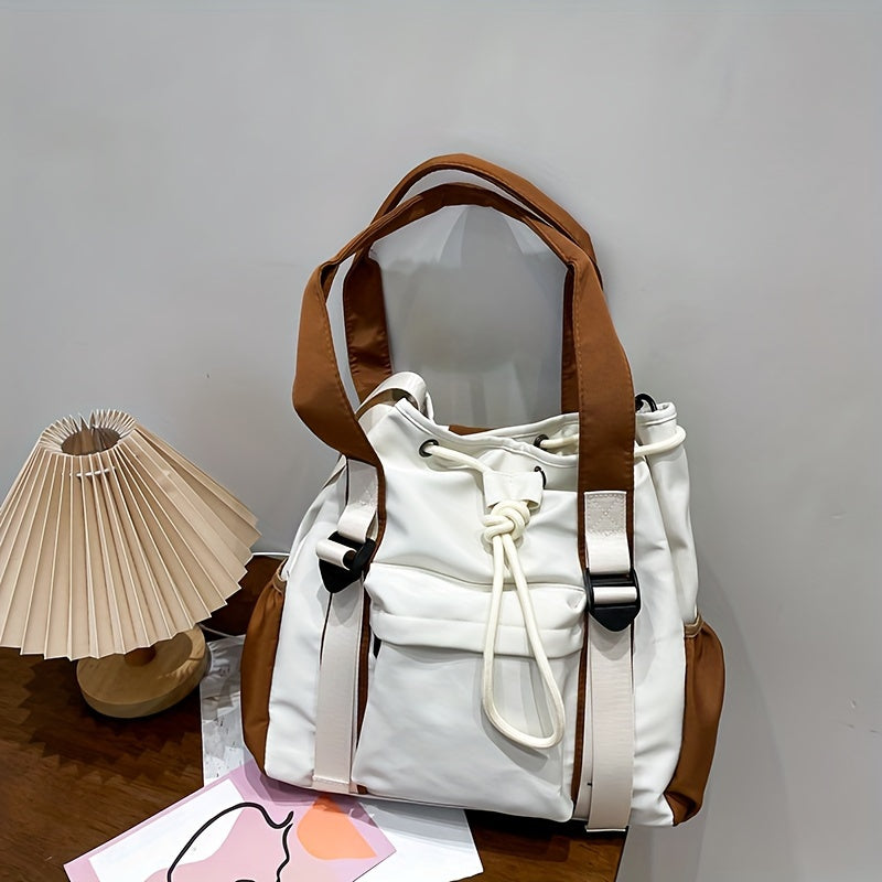 Borsa a secchiello bianca e marrone con manici, design moderno, su tavolo di legno accanto a lampada pieghevole e rivista. Accessorio moda elegante.