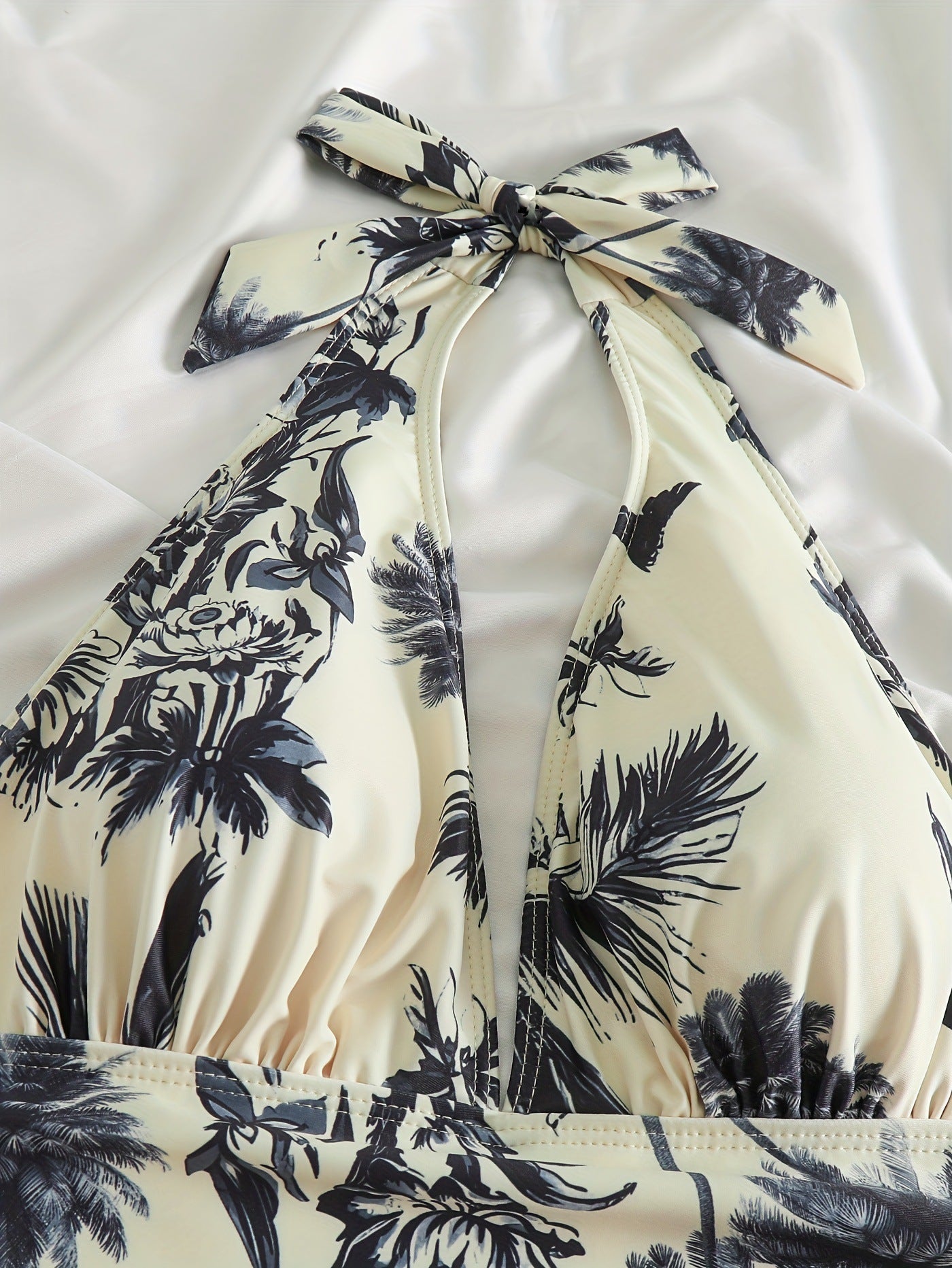Costume da bagno intero donna con stampa tropicale, scollo all'americana, fondo bianco e motivi blu navy. Elegante e ideale per l'estate.