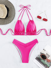 Bikini rosa a triangolo con laccetti, occhiali da sole rossi, cappello di paglia e rivista su sfondo bianco. Moda mare estiva donna.