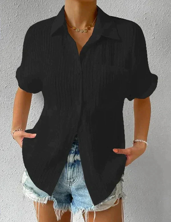 Camicia nera a maniche corte con colletto, abbinata a shorts di jeans chiari. Look casual estivo per donna, moda trendy e confortevole.