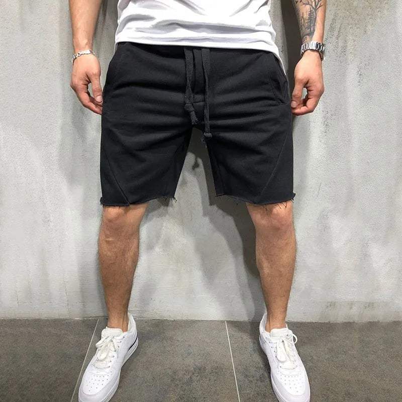 Uomo in pantaloncini neri casual, t-shirt bianca e scarpe da ginnastica bianche. Moda estiva maschile, abbigliamento sportivo urbano.