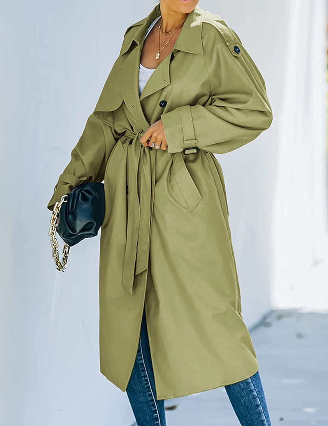 Cappotto trench verde oliva da donna, lungo, con cintura in vita, abbinato a jeans blu e borsa nera. Stile elegante e moderno per l'autunno.