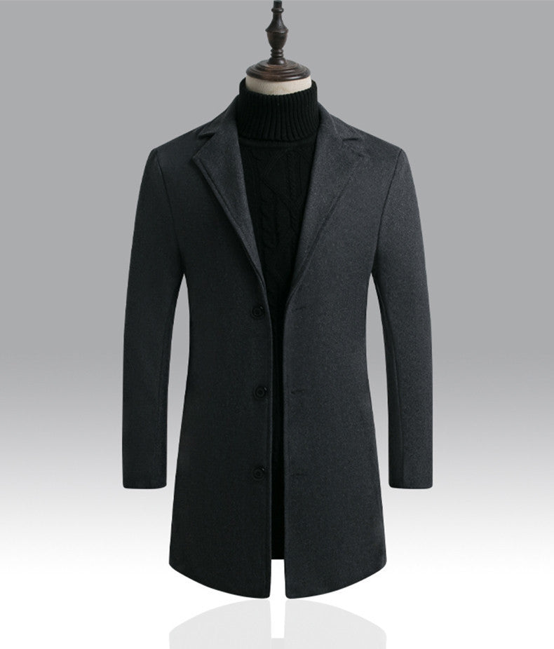 Cappotto uomo elegante grigio scuro, lungo, con bottoni, su manichino. Moda invernale, abbigliamento formale, tessuto di qualità.