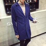 Cappotto uomo blu elegante, lungo, con bottoni, indossato sopra maglione grigio. Moda maschile autunno-inverno, stile casual chic.