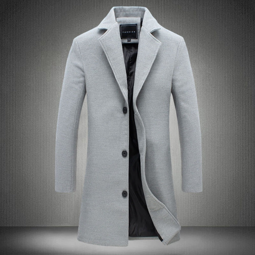 Cappotto uomo elegante grigio chiaro, lungo, con bottoni neri e fodera interna, ideale per moda invernale e look formale.