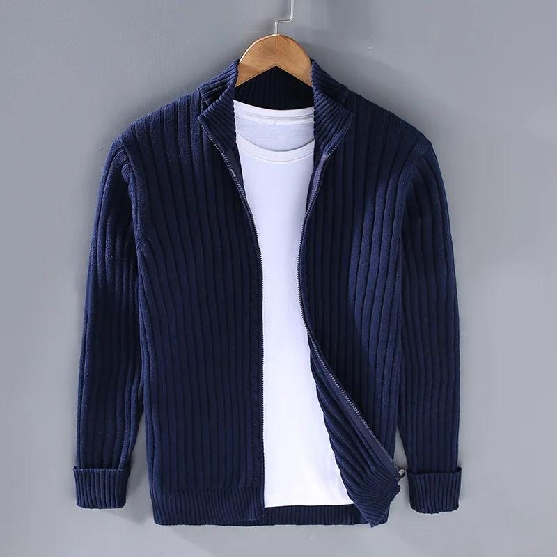 Cardigan blu a coste con zip, appeso su gruccia, sopra t-shirt bianca. Moda uomo, abbigliamento casual, maglione invernale elegante.