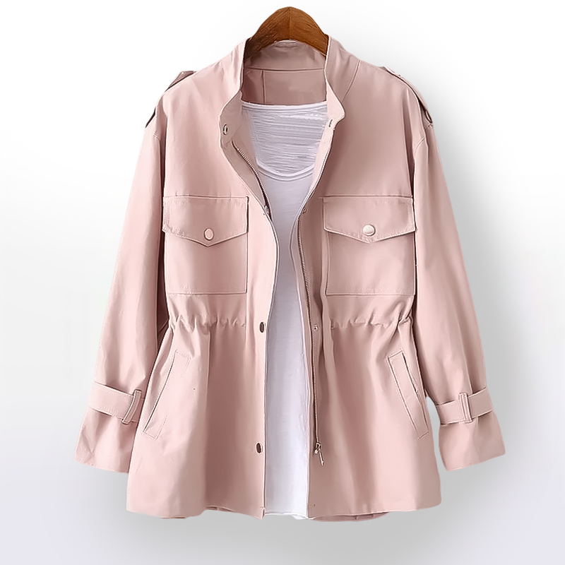 Giacca rosa chiaro da donna con tasche frontali e cintura, appesa su gruccia. Design casual, ideale per moda primaverile.