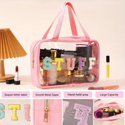 Borsa da trucco trasparente rosa con etichetta "STUFF" in paillettes, cerniera metallica liscia, ampia capacità, ideale per cosmetici e accessori.
