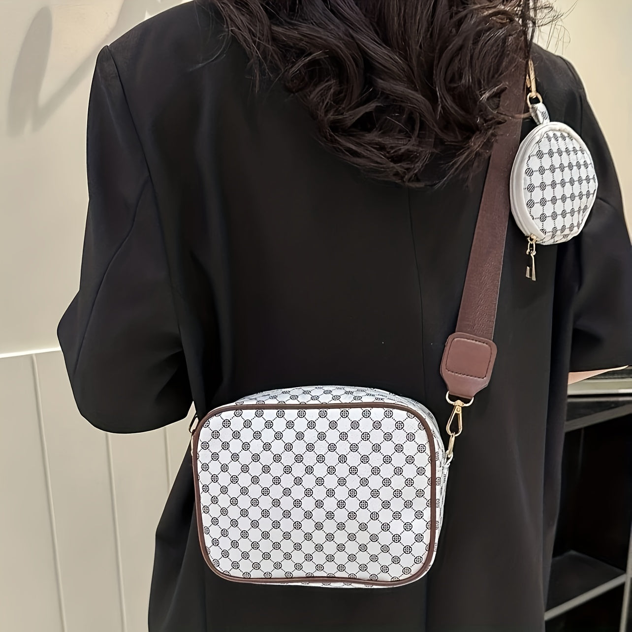 Donna con borsa a tracolla bianca e marrone con motivo a scacchi, abbinata a un piccolo portamonete rotondo. Accessorio moda elegante e moderno.