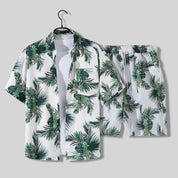 Set coordinato estivo uomo, camicia e pantaloncini con stampa foglie tropicali verdi su sfondo bianco, abbigliamento casual vacanza.