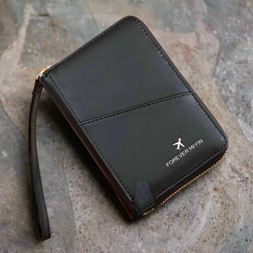 Portafoglio nero in pelle con cerniera, design compatto, marchio "Forever Mvin", su sfondo pietra. Accessorio moda elegante e funzionale.