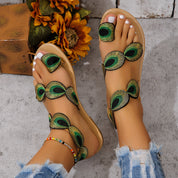 Sandali estivi da donna con decorazioni a piume di pavone, suola beige, indossati con jeans strappati. Scarpe moda casual eleganti.