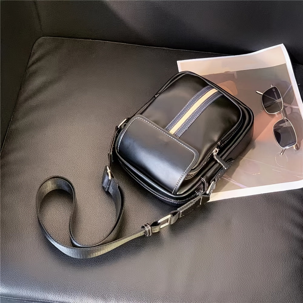 Borsa a tracolla in pelle nera su divano, con striscia decorativa blu e beige, accanto a occhiali da sole e rivista. Accessorio moda elegante.