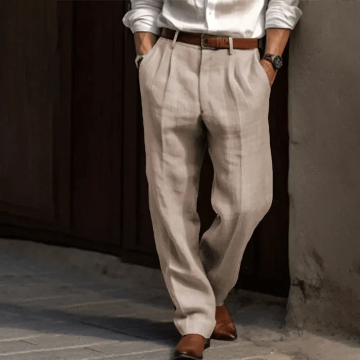 Pantaloni uomo eleganti beige in lino, abbinati a camicia bianca e cintura marrone, perfetti per look estivo casual-chic.