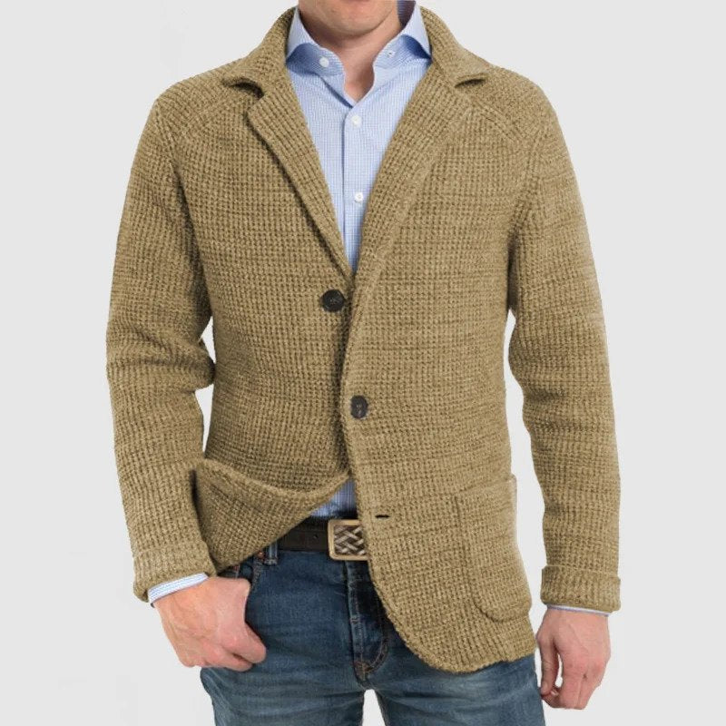 Giacca uomo beige in maglia, stile casual, con bottoni e tasche frontali, indossata su camicia azzurra e jeans. Moda maschile autunnale.