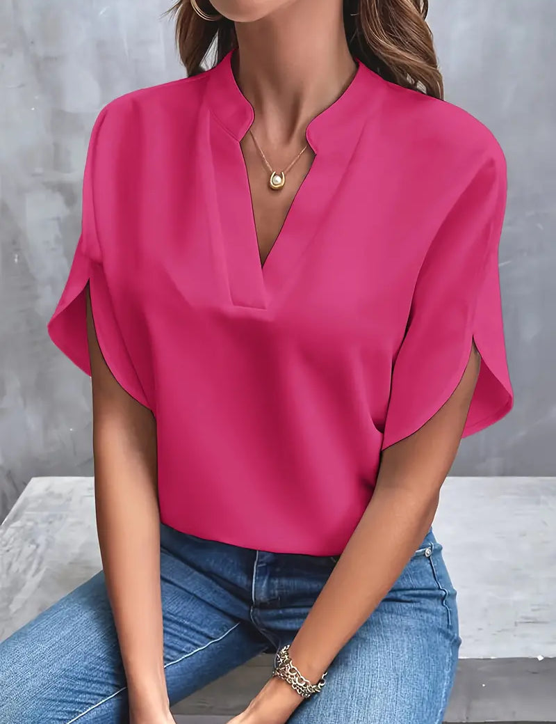 Blusa rosa fucsia elegante da donna, maniche corte, scollo a V, abbinata a jeans. Moda casual femminile, abbigliamento estivo trendy.