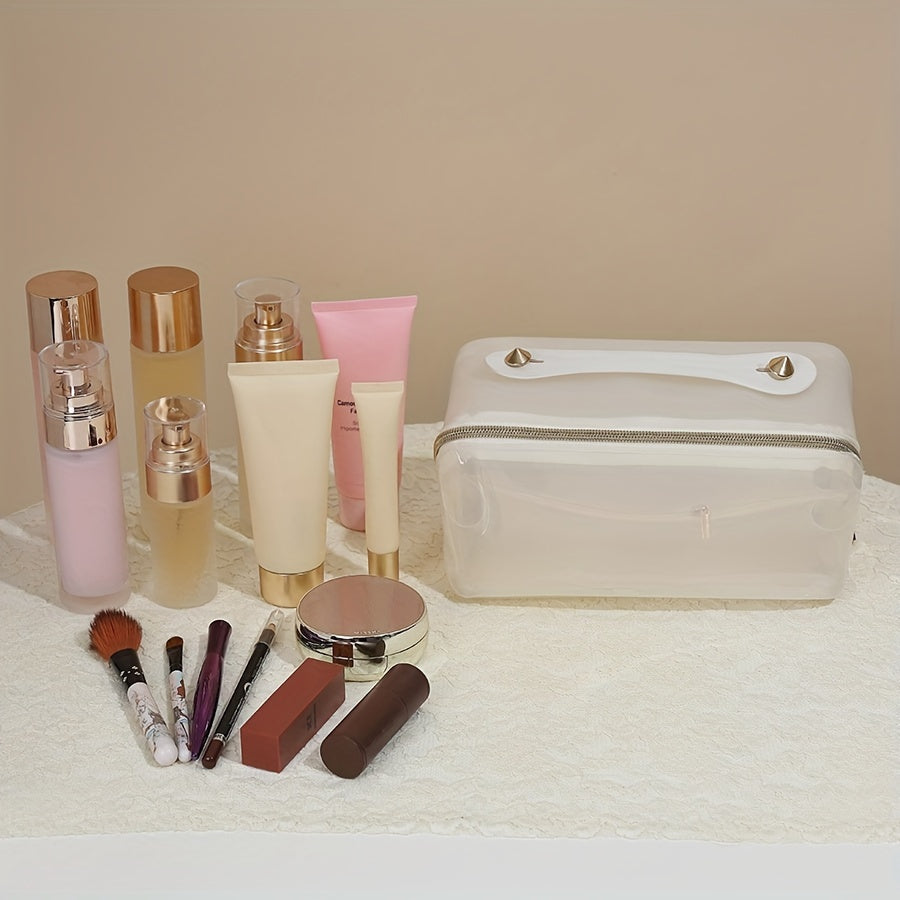 Set di cosmetici su tavolo bianco: flaconi crema, rossetto, pennelli trucco, specchio e pochette trasparente. Prodotti bellezza e cura pelle.