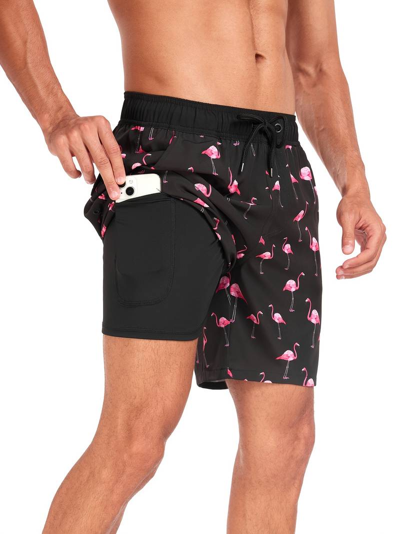 Uomo in costume da bagno nero con fenicotteri rosa, tasca laterale con smartphone. Moda mare, abbigliamento estivo, pantaloncini da nuoto.