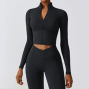Giacca sportiva nera da donna a maniche lunghe con zip, abbinata a leggings a vita alta. Abbigliamento fitness elegante e funzionale.