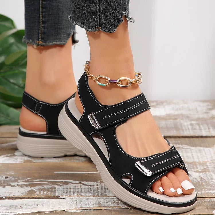 Sandali neri da donna con suola spessa, cinturini regolabili in velcro, indossati con jeans strappati. Scarpe estive comode e alla moda.