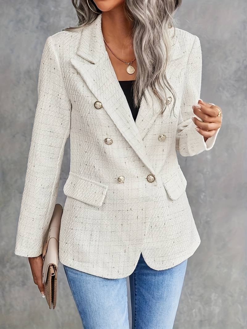 Giacca doppiopetto bianca elegante, bottoni dorati, indossata con jeans blu. Look chic e moderno per donna. Moda autunno-inverno.