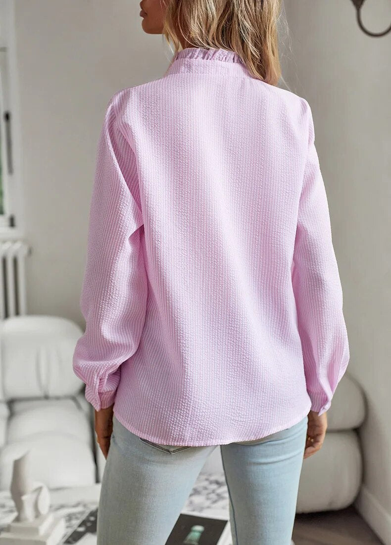Camicia donna rosa pastello, tessuto a trama leggera, maniche lunghe, collo alto, indossata con jeans chiari. Moda casual femminile.