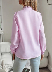 Camicia donna rosa pastello, tessuto a trama leggera, maniche lunghe, collo alto, indossata con jeans chiari. Moda casual femminile.