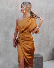 Donna in abito monospalla color oro, elegante e lucido, con pochette marrone. Moda femminile, abbigliamento da sera, stile sofisticato.