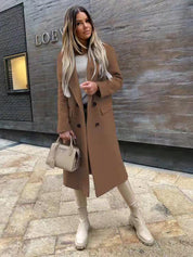 Donna con cappotto marrone, stivali beige e borsa Prada, posa davanti a un edificio moderno. Moda autunnale elegante, look urbano sofisticato.