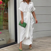 Donna con abito bianco lungo drappeggiato, sandali verdi e borsa verde. Moda estiva elegante, abbigliamento casual chic, tendenze 2023.