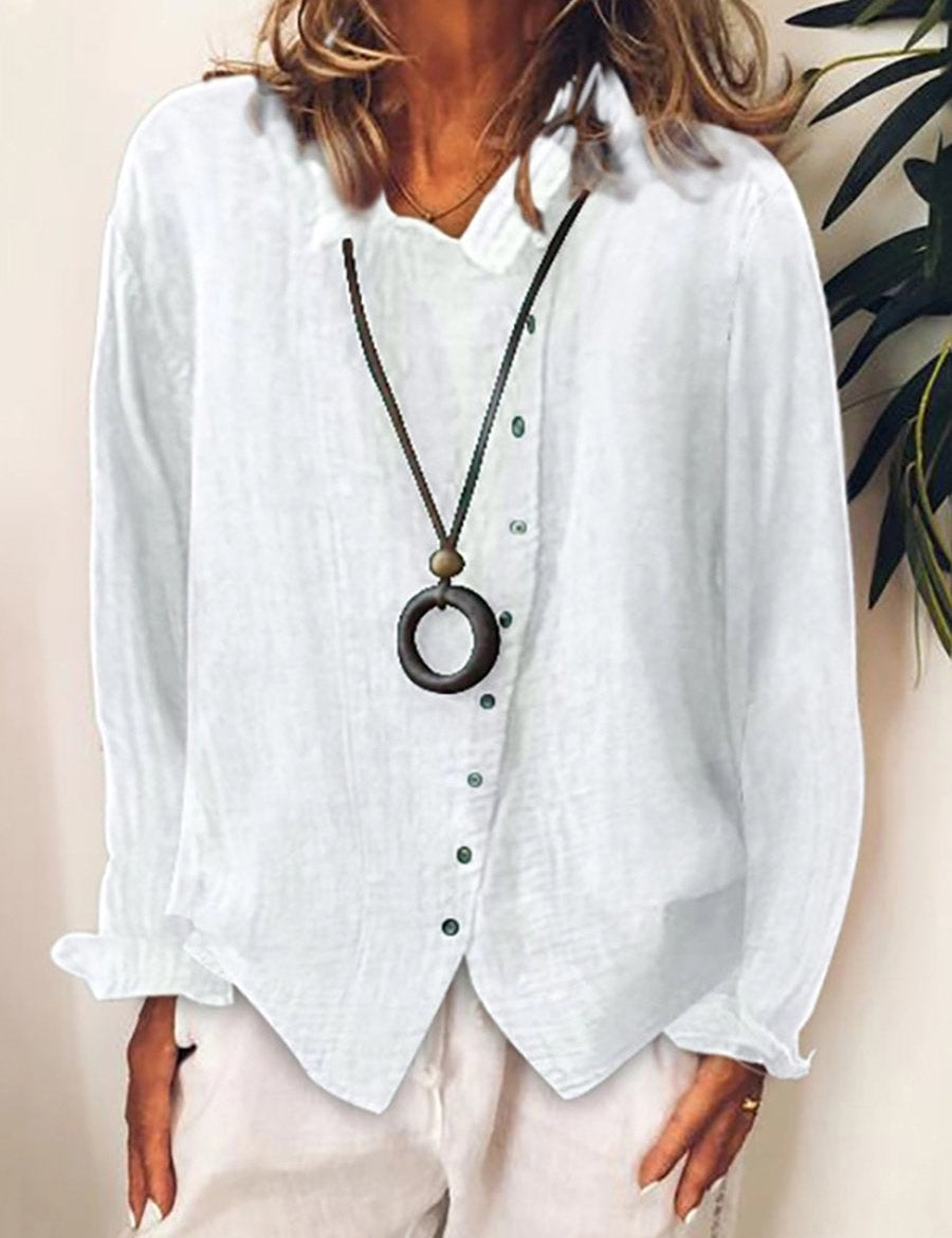 Camicia bianca in lino da donna con bottoni verdi, abbinata a collana con ciondolo circolare. Moda casual elegante, abbigliamento estivo.