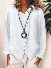 Camicia bianca in lino da donna con bottoni verdi, abbinata a collana con ciondolo circolare. Moda casual elegante, abbigliamento estivo.
