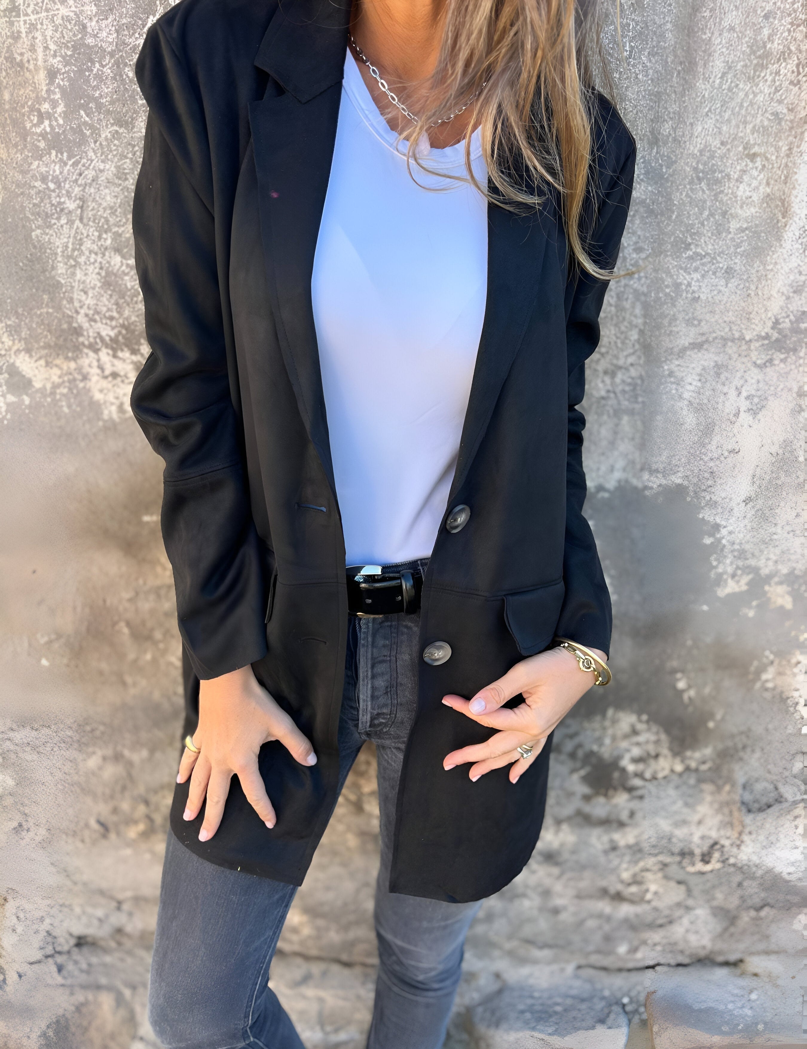 Donna con giacca nera elegante, maglietta bianca e jeans grigi. Moda casual chic, abbigliamento autunnale, stile urbano femminile.