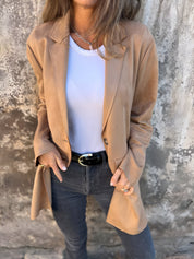 Donna con giacca beige, maglietta bianca e jeans neri. Moda casual elegante, abbigliamento autunnale, stile urbano femminile.