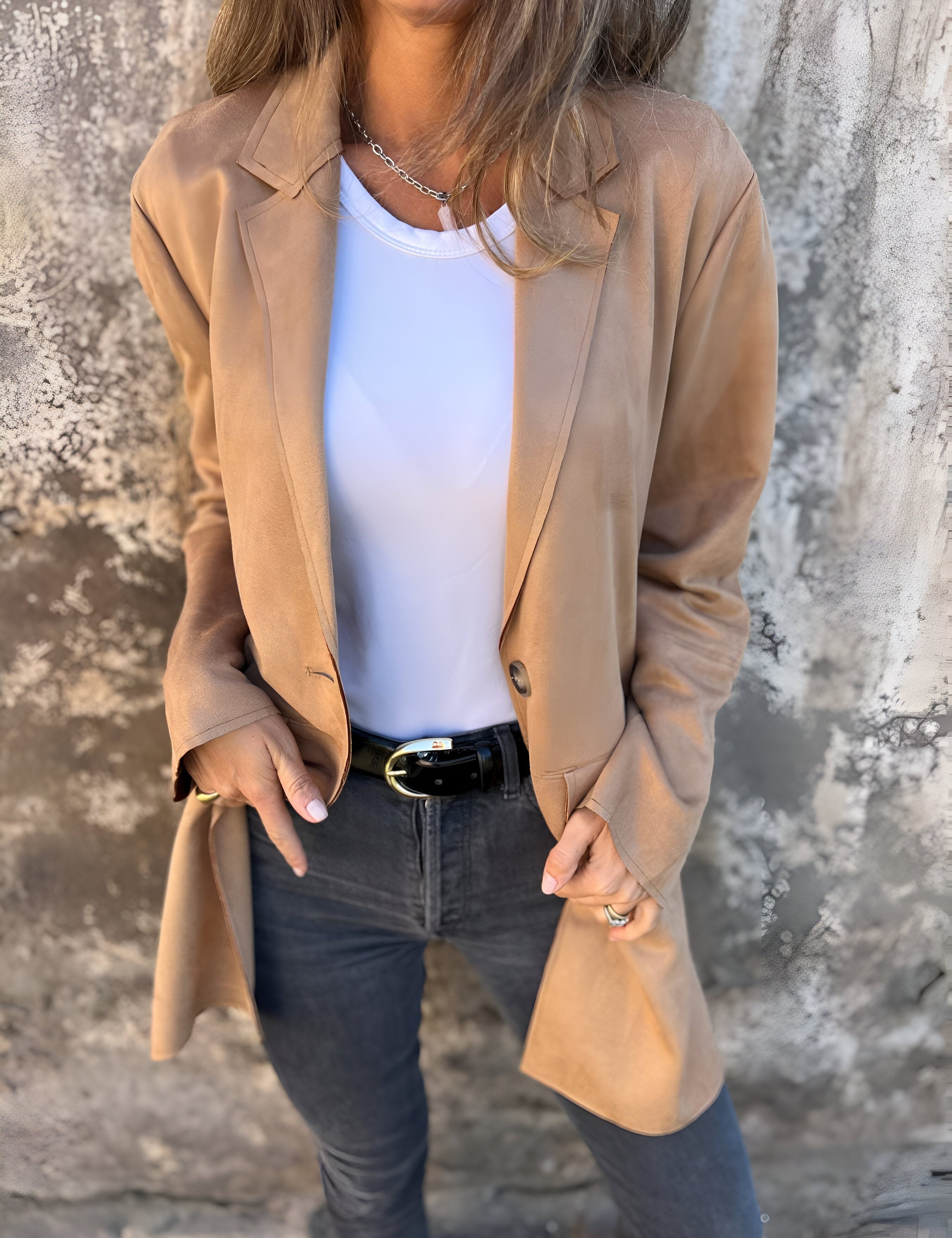Donna con giacca beige, maglietta bianca e jeans neri. Moda casual elegante, abbigliamento autunnale, stile urbano femminile.