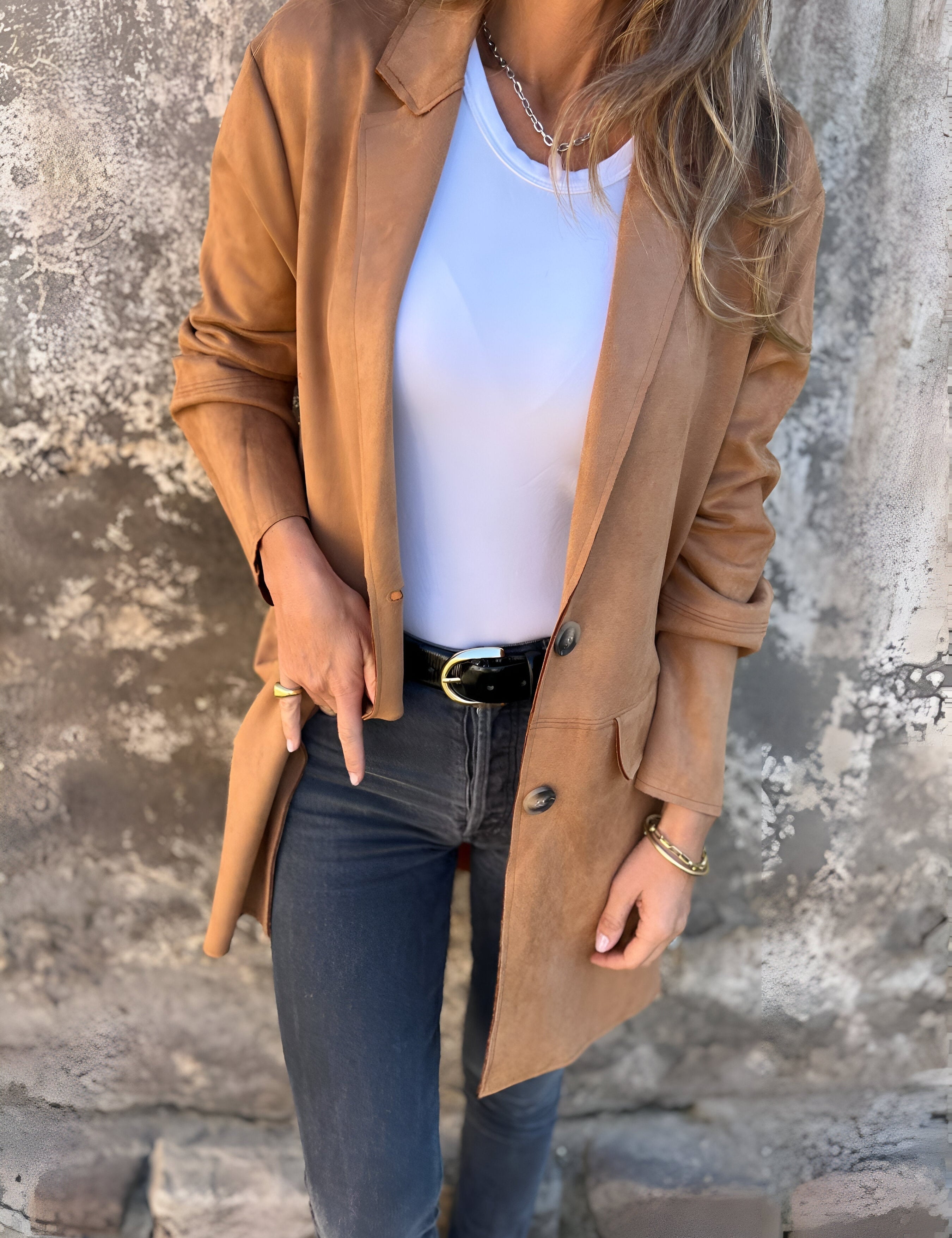 Giacca in pelle marrone da donna, abbinata a maglietta bianca e jeans neri. Look casual chic, moda autunnale, stile urbano elegante.