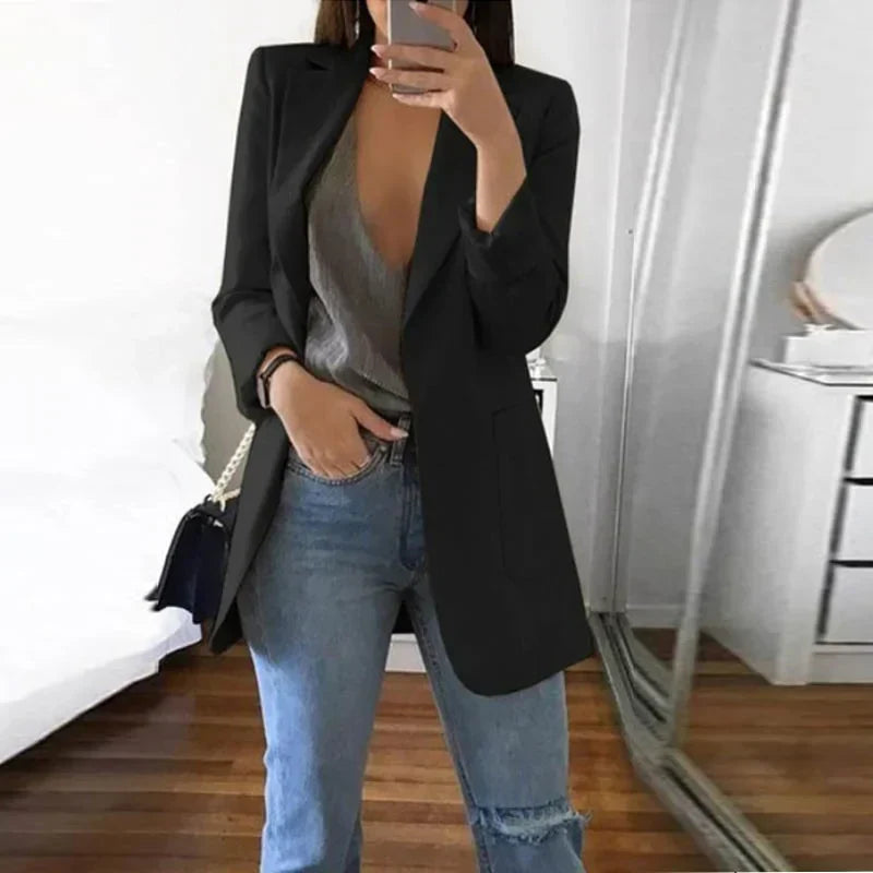 Giacca nera elegante da donna, abbinata a top grigio scollato e jeans strappati, moda casual chic, perfetta per look autunnali.