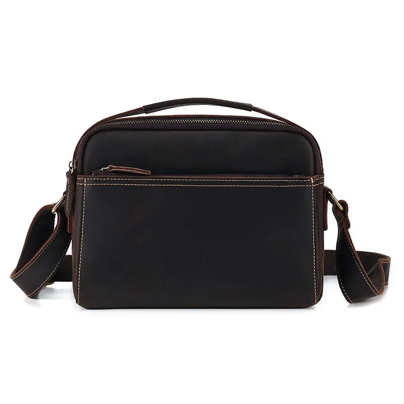 Borsa a tracolla in pelle marrone scuro, design elegante e compatto, con cerniera frontale e tracolla regolabile. Accessorio moda uomo/donna.