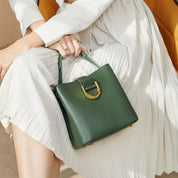 Donna con borsa a mano verde in pelle, design elegante, chiusura dorata, abito bianco plissettato. Accessorio moda femminile di lusso.