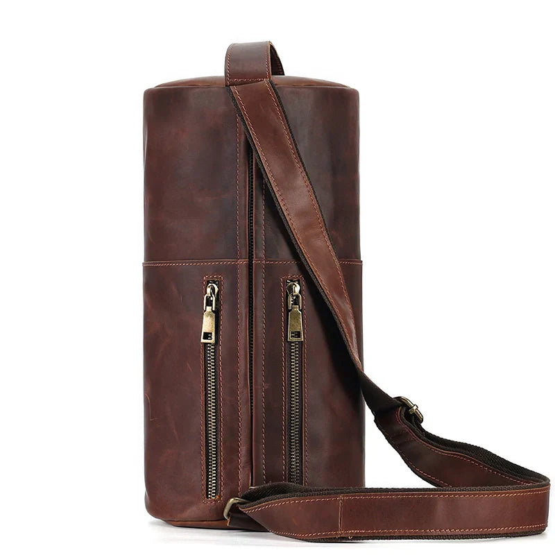 Borsa a tracolla cilindrica in pelle marrone con doppia cerniera e tracolla regolabile. Design elegante e pratico per uomo e donna.