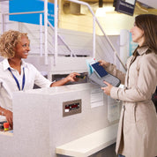 Donna al check-in aereo, consegna passaporto e biglietto a impiegata sorridente. Viaggio, aeroporto, servizio clienti, partenza volo.