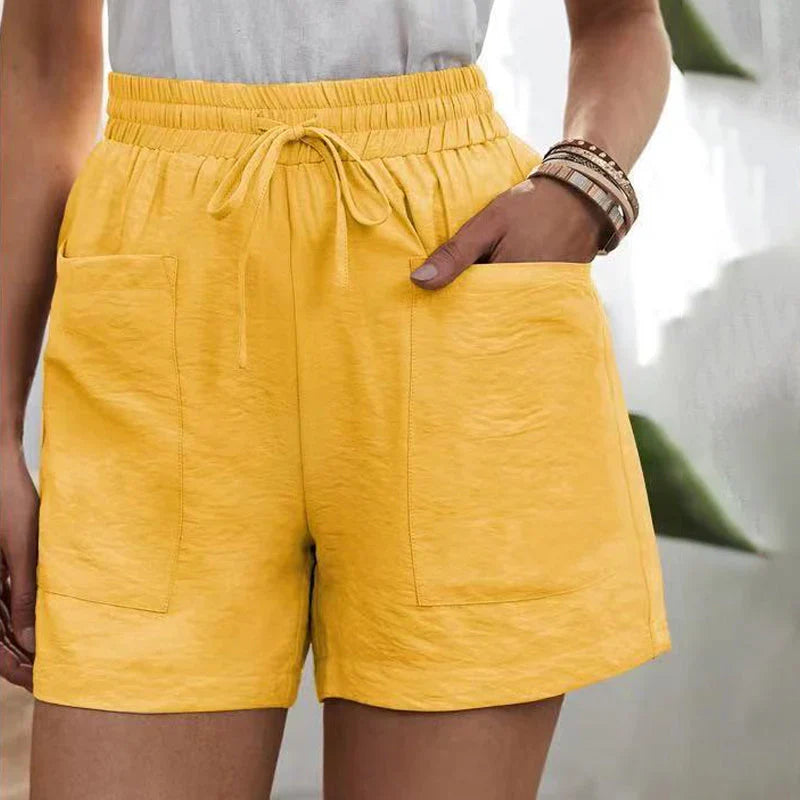 Shorts gialli da donna con tasche, elastico in vita e laccio, indossati con top bianco. Stile casual estivo, moda femminile.