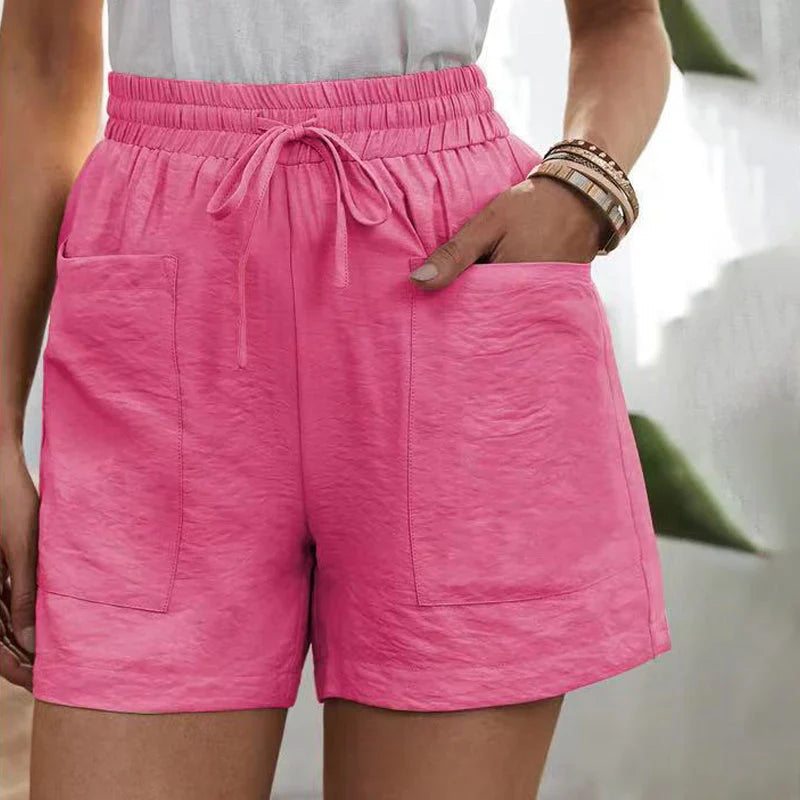 Shorts rosa da donna con tasche, elastico in vita e laccio, indossati con maglietta bianca. Stile casual estivo, moda femminile.