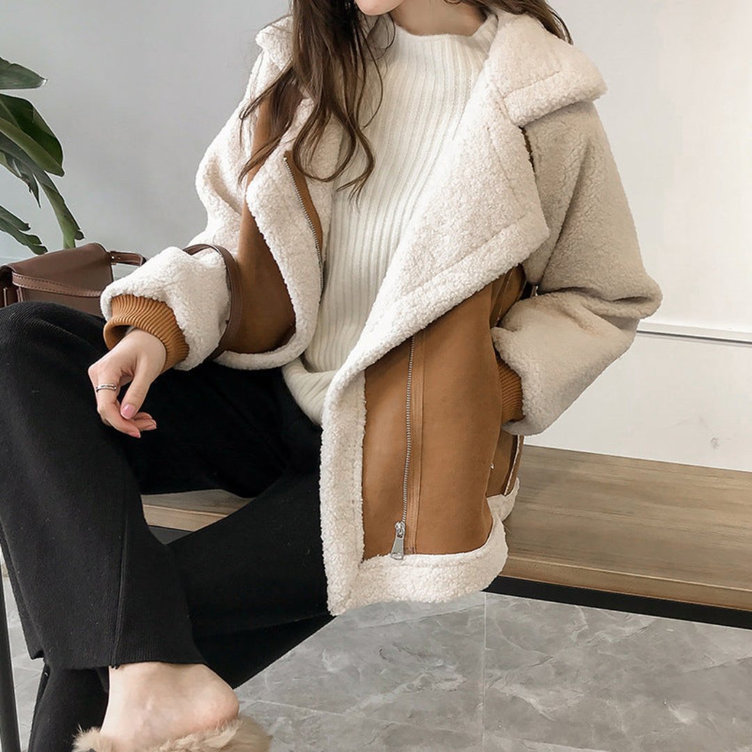 Giacca invernale donna in shearling beige e marrone, abbinata a maglione bianco e pantaloni neri. Moda casual, abbigliamento caldo e trendy.