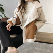 Giacca invernale donna in shearling beige e marrone, abbinata a maglione bianco e pantaloni neri. Moda casual, abbigliamento caldo e trendy.