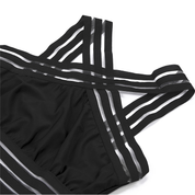 Top sportivo nero con spalline incrociate a righe bianche e nere, design moderno, tessuto elasticizzato, ideale per allenamento e yoga.
