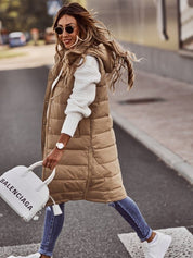 Donna alla moda con gilet lungo beige, maglione bianco, jeans attillati e borsa Balenciaga bianca. Look casual chic autunnale.