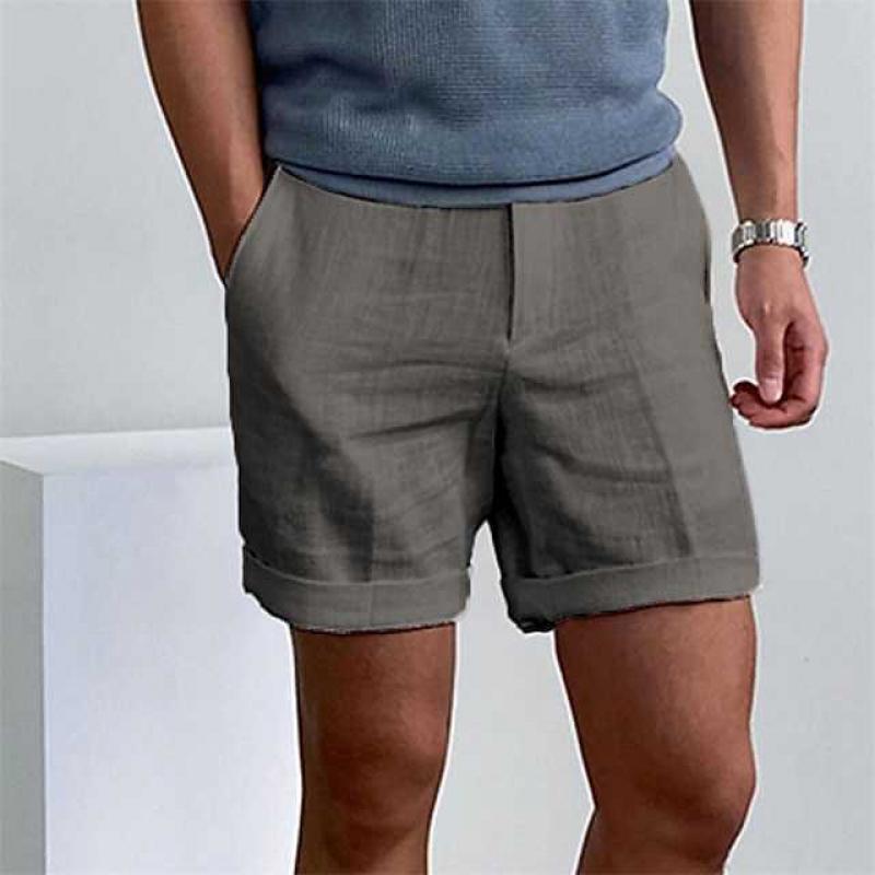 Uomo con pantaloncini grigi eleganti, maglietta blu, orologio al polso. Moda estiva maschile, abbigliamento casual chic.