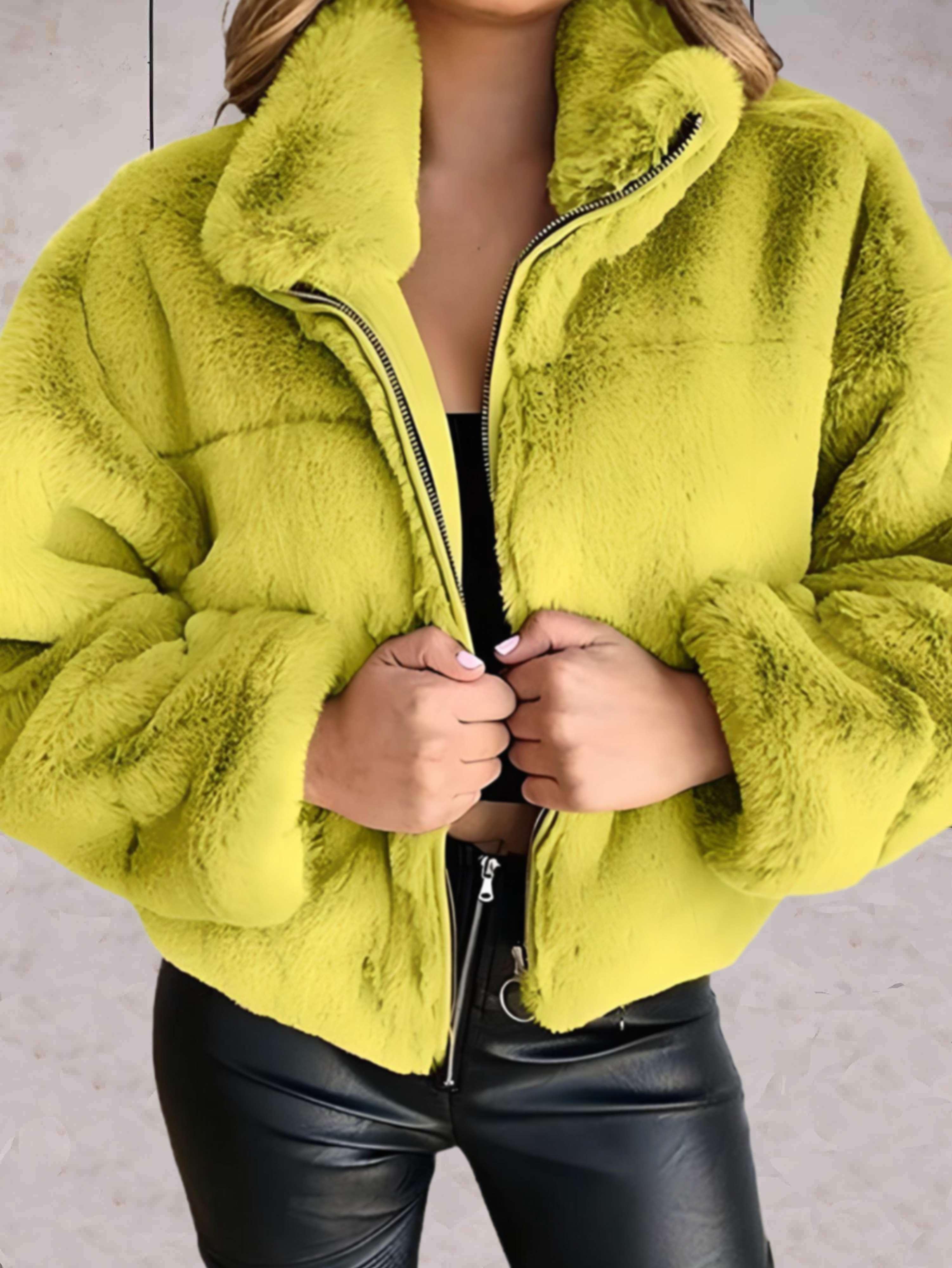 Giacca in ecopelliccia verde lime, donna, con zip frontale, indossata su top nero e pantaloni in pelle. Moda autunnale, stile casual chic.